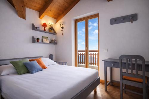 a bedroom with a bed and a window and a desk at LA PULCE INNEVATA - Mansarda a due passi dal cielo - Dolomiti Affitti in Passo Rolle
