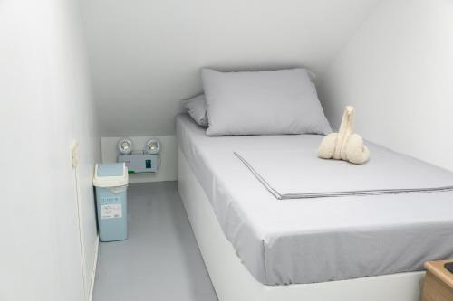 a small bedroom with a white bed with a stuffed animal on it at Wanderers Backpacker Condotel in Pusok