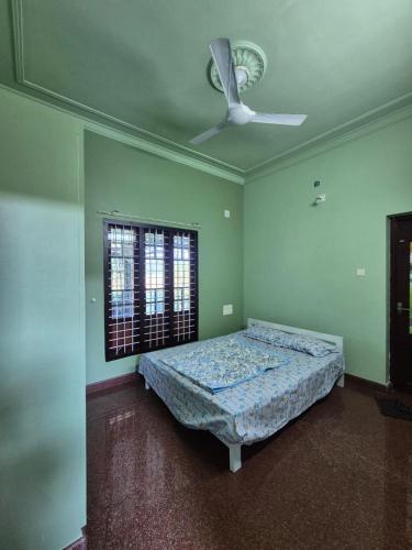 a bedroom with a bed and a ceiling fan at meadowell homestay in Kizhake Chālakudi
