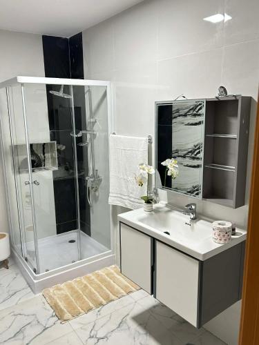 a white bathroom with a shower and a sink at Hotel Pirâmide in Igreja