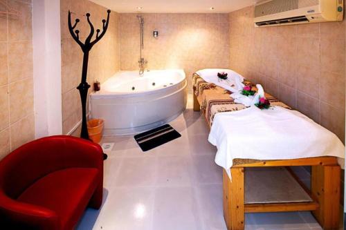 a bathroom with a tub and a red chair at City Point Hotel in Manama