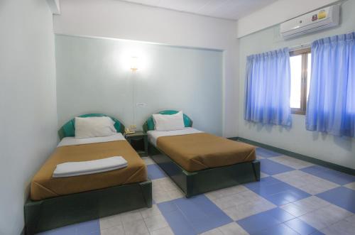 two beds in a room with blue curtains at Grand Leo Hotel in Khon Kaen