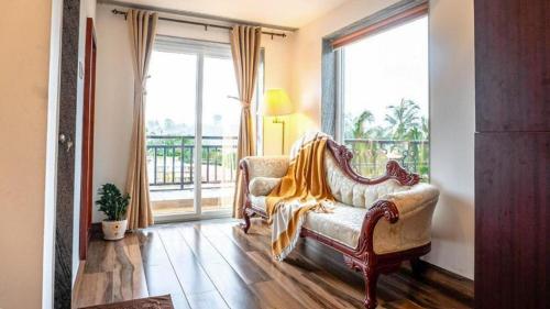 a living room with a couch and a large window at Cana Boutique Stay in Porvorim