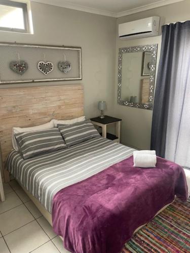 ein Schlafzimmer mit einem großen Bett und einer lila Decke in der Unterkunft Anas Inn in Walvis Bay