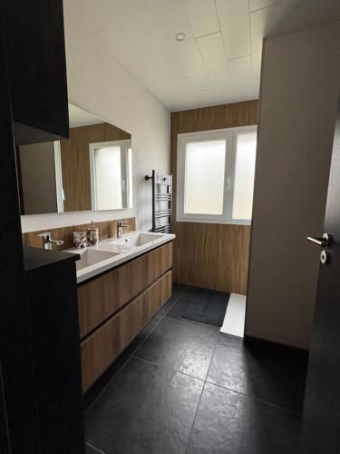 a bathroom with two sinks and a large mirror at Maison chaleureuse de village - location à la chambres in Lanans