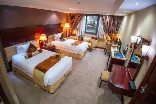 a hotel room with two beds and a desk at Grand Legacy Hotel in Kigali