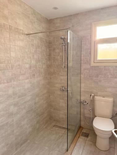 a bathroom with a toilet and a glass shower at DEight by The Dream Stays in New cairo