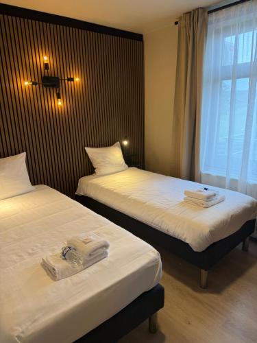 two beds in a hotel room with towels on them at Hotel Le Relais de Pommard in Francorchamps