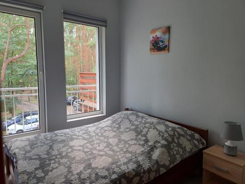 a bedroom with a bed and two windows at Apartament nad Jeziorem Sławskim in Radzyń