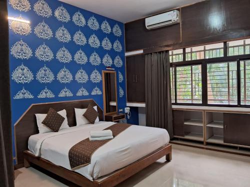 a bedroom with a bed and a blue wall at Advaitha Serenity Resorts in Kālvādi