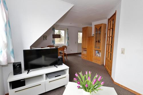 a living room with a television on a white cabinet at Schwedenhaus Westensee 2 OG in Groß Vollstedt