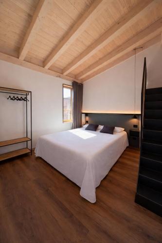 a bedroom with a white bed and a wooden ceiling at Le Calle Holiday Apartments in Nago-Torbole