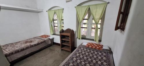 a room with two beds and two windows at Saraswati Kunj in mayapur
