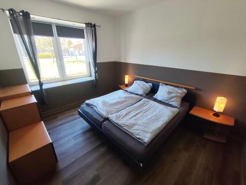 a bedroom with a bed with two lamps and a window at Ferienwohnung Alte Fleischerei in Lauchhammer