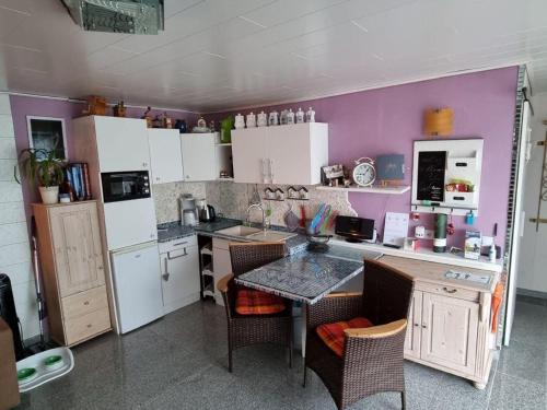 a kitchen with white cabinets and a table with chairs at Sonnenhaus in Neuenkirchen