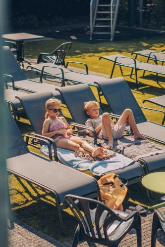 two children sitting in chairs in a yard at Veluwepark de Bosgraaf - Glamping in Lieren