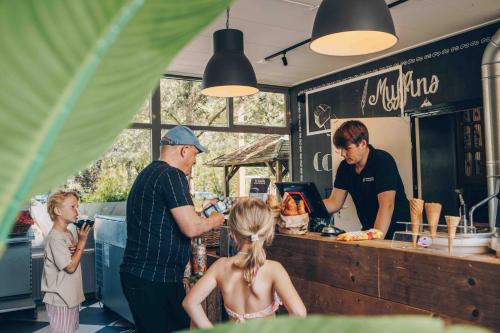 a man and a woman and a child standing in a kitchen at Veluwepark de Bosgraaf - Glamping in Lieren