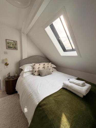 a bedroom with a large white bed with a skylight at The Old Bank in Moffat