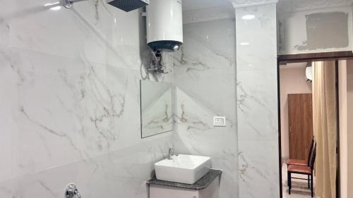 a white bathroom with a sink and a mirror at Surmila International Hotel in Āsansol