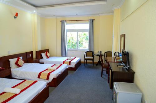a hotel room with three beds and a television at Khách Sạn Á Châu Cần Thơ in Can Tho