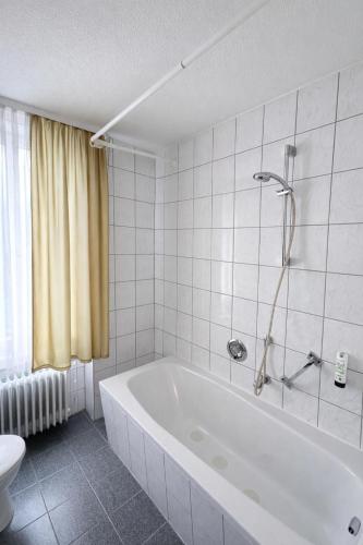 biała łazienka z wanną i toaletą w obiekcie Hotel Brigach w mieście Villingen-Schwenningen