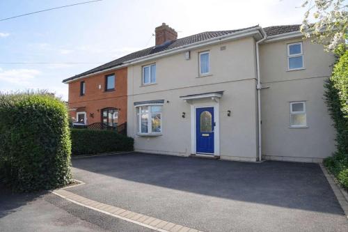 a white house with a blue door on a driveway at Chic 5 Bedroom House with Private Parking & Garden in Bristol