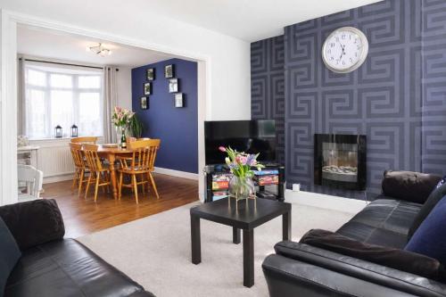 a living room with a couch and a clock on the wall at Chic 5 Bedroom House with Private Parking & Garden in Bristol