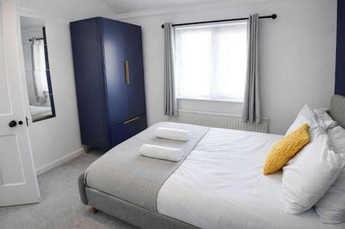 a bedroom with a blue cabinet and a bed with two towels at Chic 5 Bedroom House with Private Parking & Garden in Bristol