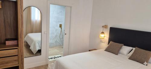 a bedroom with a large white bed and a mirror at Las Casitas del Canal Acueducto in Segovia
