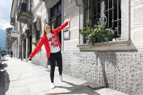 a woman in a red jacket jumping on a street at Palazzo Pellanda in Domodossola