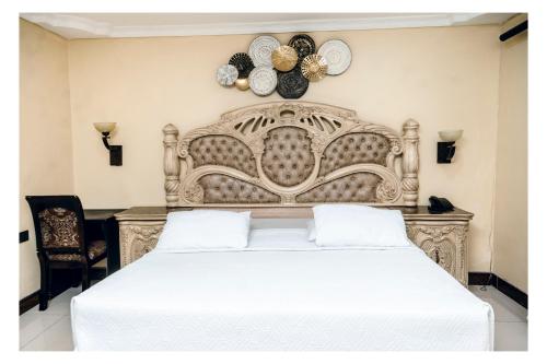 a bedroom with a large white bed with plates on the wall at Leon's Hotel in Choma