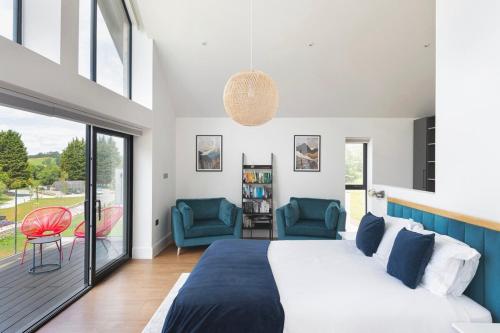 a bedroom with a large bed and two chairs at Bluebell Barn - Cookswood in Holcombe
