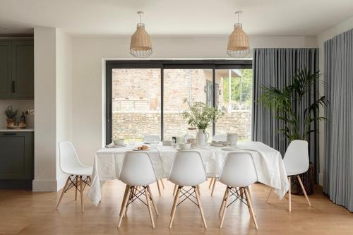 a white dining room with a white table and chairs at Bluebell Barn - Cookswood in Holcombe