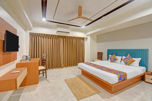 a hotel room with a bed and a flat screen tv at FabHotel New Moshi Grrand in Pune
