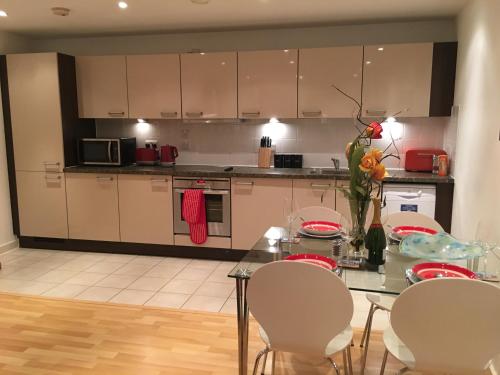 a kitchen with a table and white cabinets and a table and chairs at Gunwharf Quays Harbour Apartments in Portsmouth