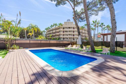 a swimming pool with a wooden deck and a building at Villa Els Pins in El Arenal