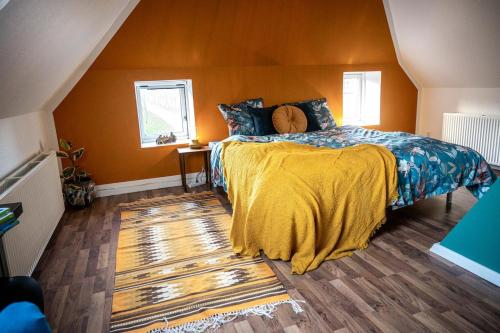 a bedroom with a bed with a yellow blanket on it at Art Apartment Sønderbygaard in Vinderup