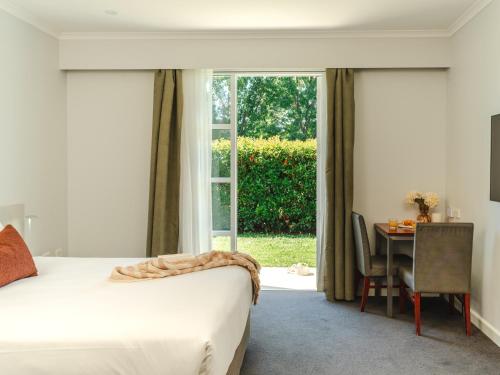 a bedroom with a bed and a table and a window at Punthill Narrabundah in Canberra