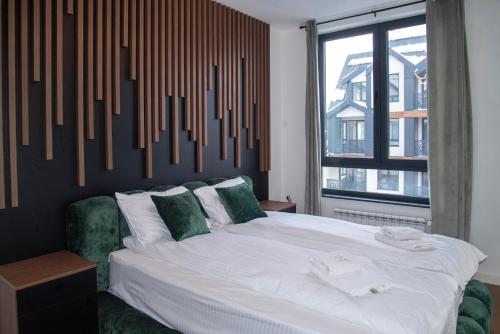 a bedroom with a large bed and a large window at Modena Resort Spa & Wellness Zlatibor in Zlatibor