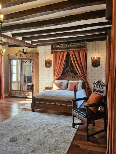 a bedroom with a canopy bed and a chair at Château de Naie in Avon-les-Roches