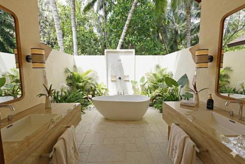 a bathroom with a large tub and two sinks at Fiyavalhu Resort Maldives in Mandhoo