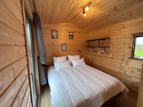 a bedroom with a bed in a wooden cabin at La Tiny du Clos Ernest in Cheminot
