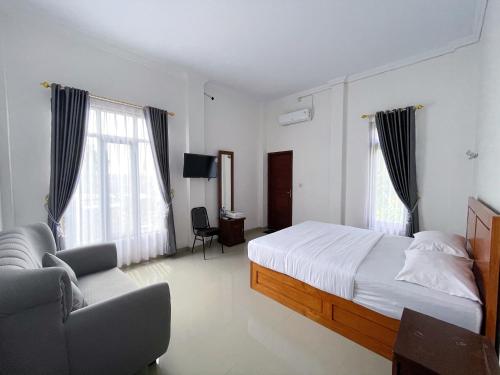 a bedroom with a bed and a couch and windows at Guest House Primitif in Temon
