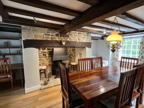 a dining room with a wooden table and a fireplace at Ivy Cottage in West Lulworth