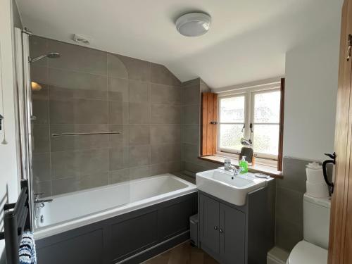a bathroom with a white tub and a sink at Ivy Cottage in West Lulworth
