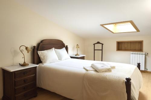 a bedroom with a large white bed and a nightstand at Casa da Estação in Torre de Moncorvo