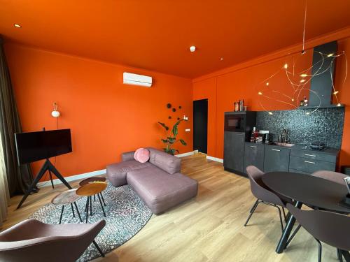 a living room with orange walls and a couch and a table at Fortuna Suites in Middelburg