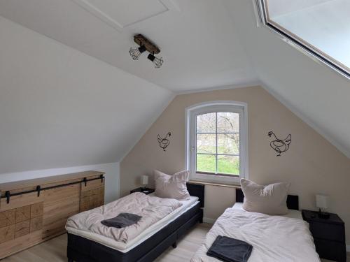 a attic room with two beds and a window at Landhaus Freche Socke in Buchhorst