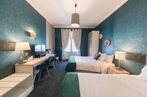 a hotel room with two beds and a desk at Hotel Mondial in Tours