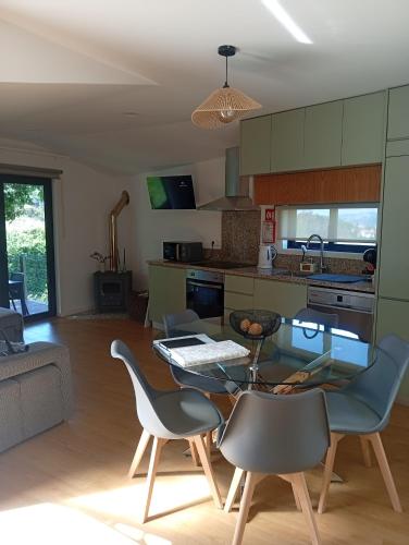 a kitchen and living room with a glass table and chairs at Refúgio Da Pinheira in Marco de Canaveses